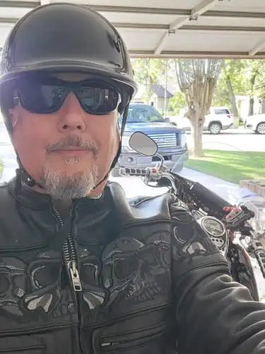 Biker wearing a beanie half helmet from beaniehelmets.com and sunglasses with leather jacket.