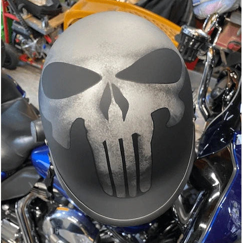 Motorcycle polo style beanie helmet with Punisher skull design on a motorcycle in a garage setting
